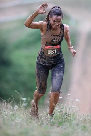 Ragazza che corre una gara di trail running nel fango